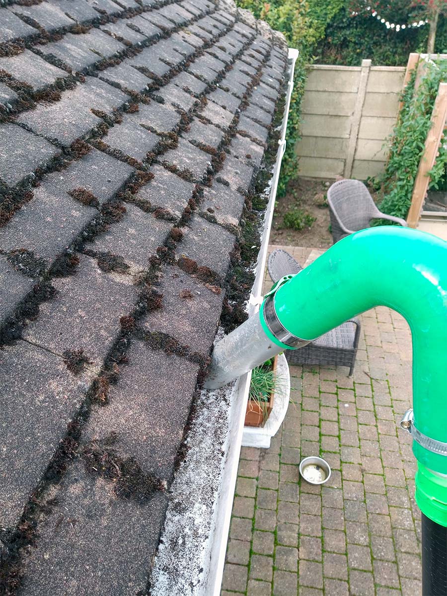 Vacuuming gutter to clear moss